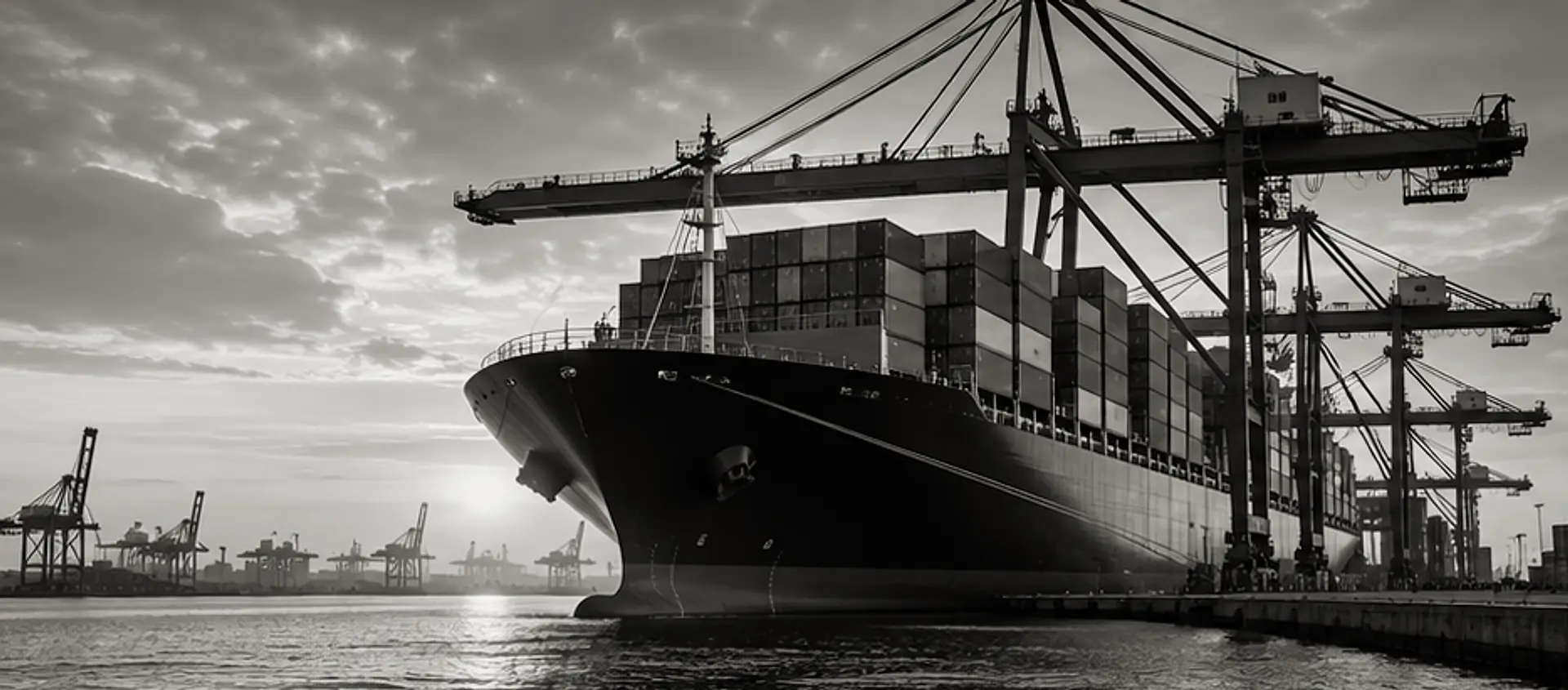Containerschip aan de kade onder containerkranen in een haventerminal bij schemering